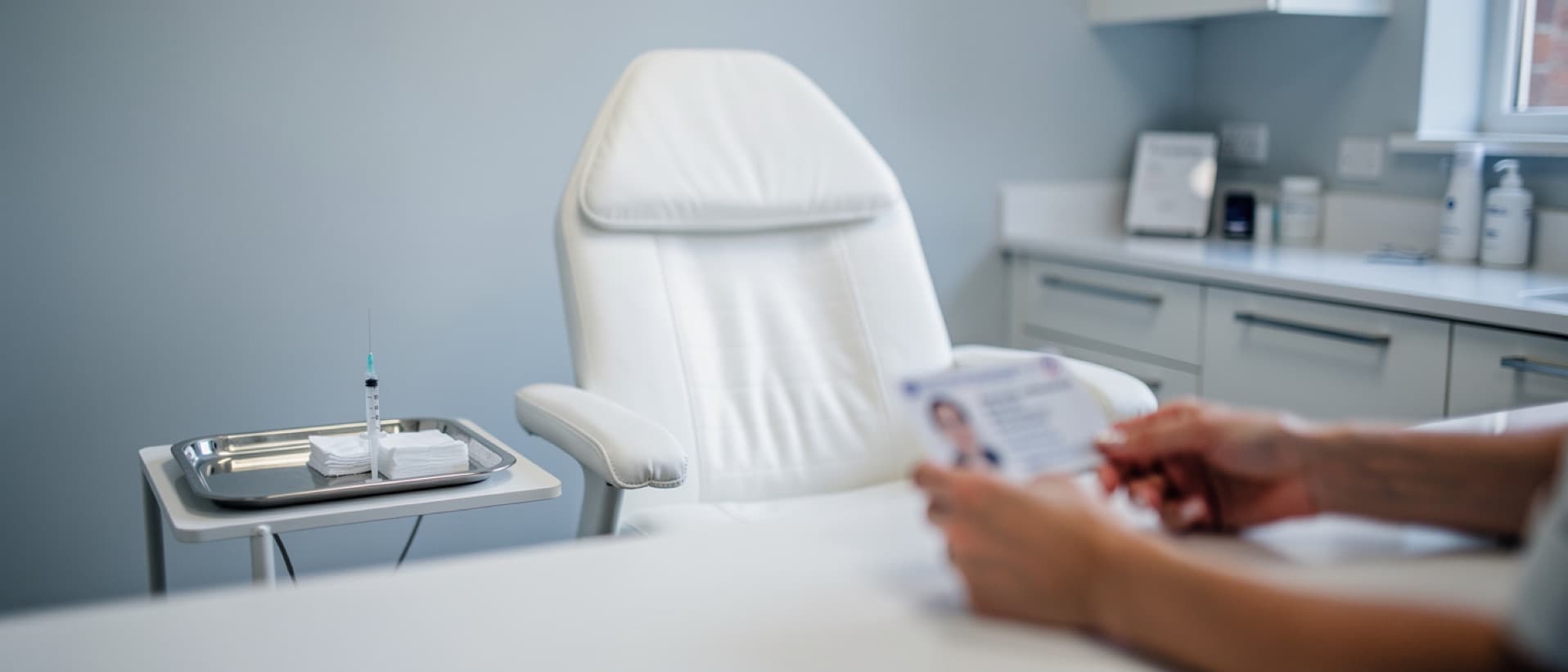Clinic receptionist checking photo ID beside a treatment chair, as the UK lip filler age limit requires