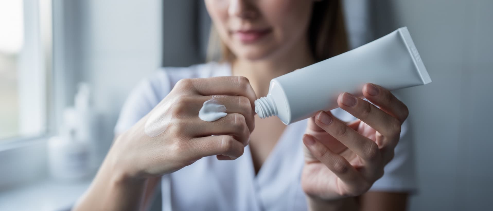 Woman applying cream from a plain tube to the back of her hand, for ruxolitinib cream as a vitiligo treatment